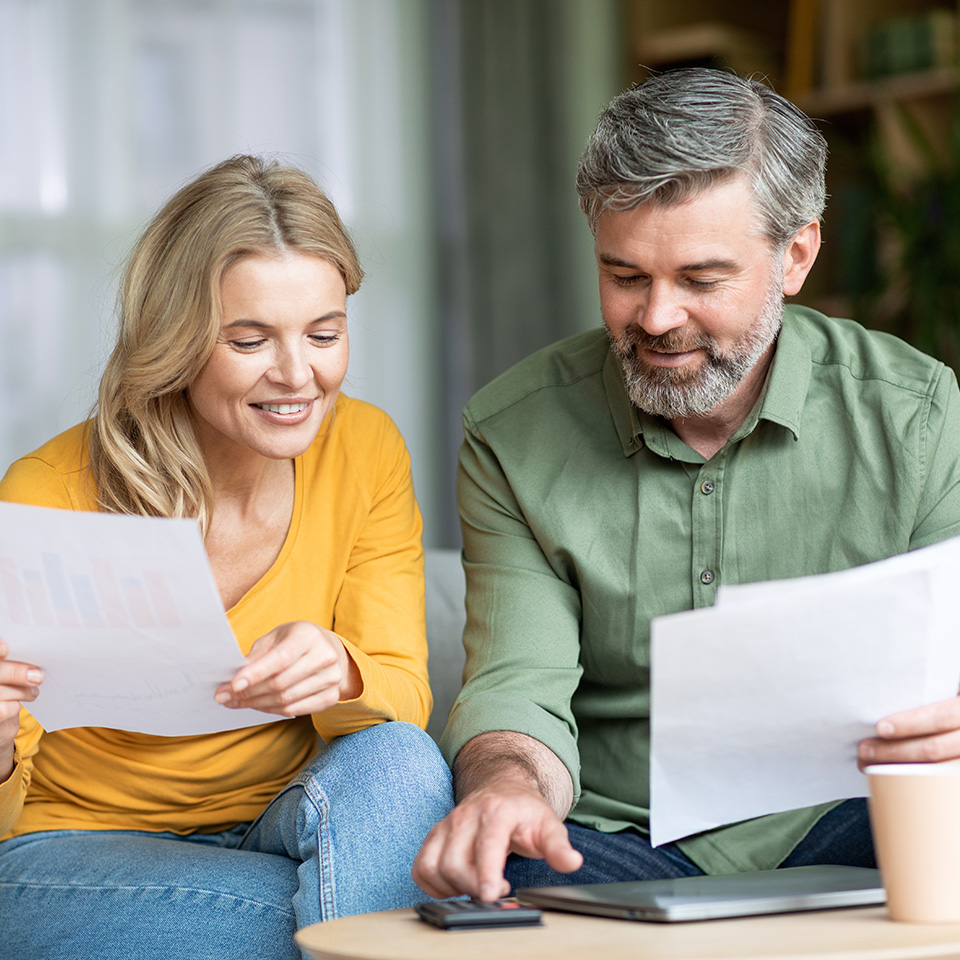 Eine Frau und ein Mann sitzen an einem Tisch und rechnen etwas nach