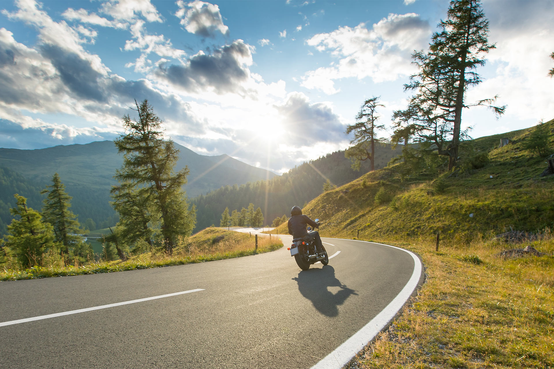 Eine Person fährt Motorrad an einem sonnigen Tag in den Bergen