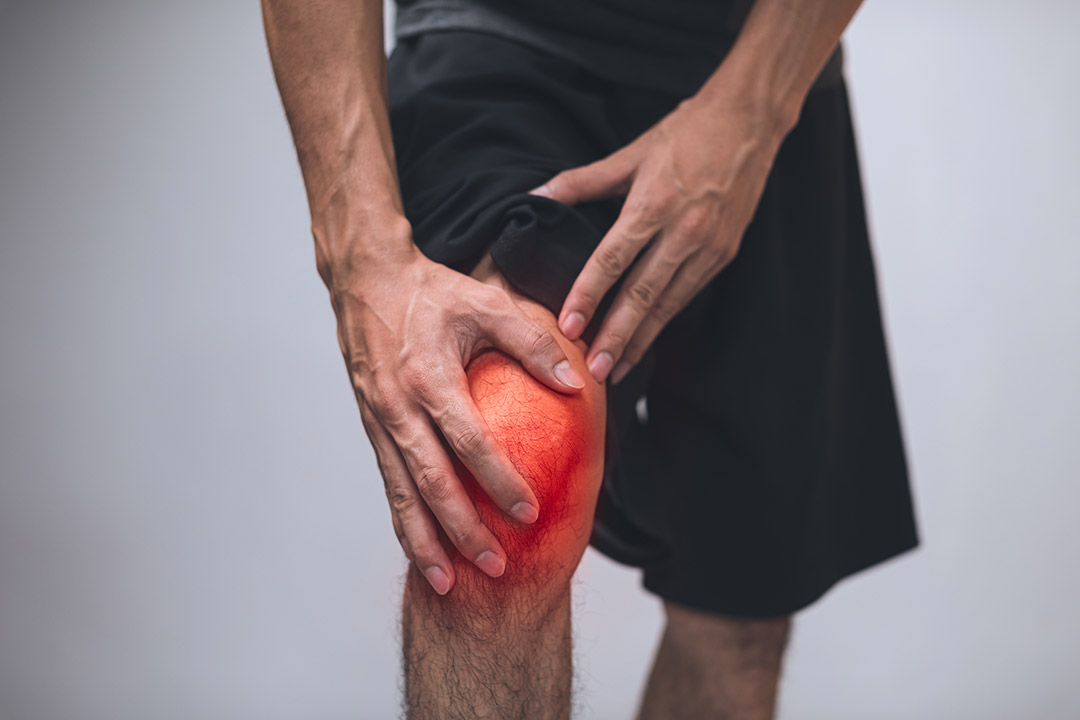 Ein Mann hält sich sein schmerzendes Knie fest